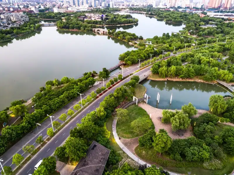 Vista aérea de um parque urbano com lagos e vegetação exuberante, ideal para atividades ao ar livre e lazer, destacando a harmonia entre a natureza e a cidade.