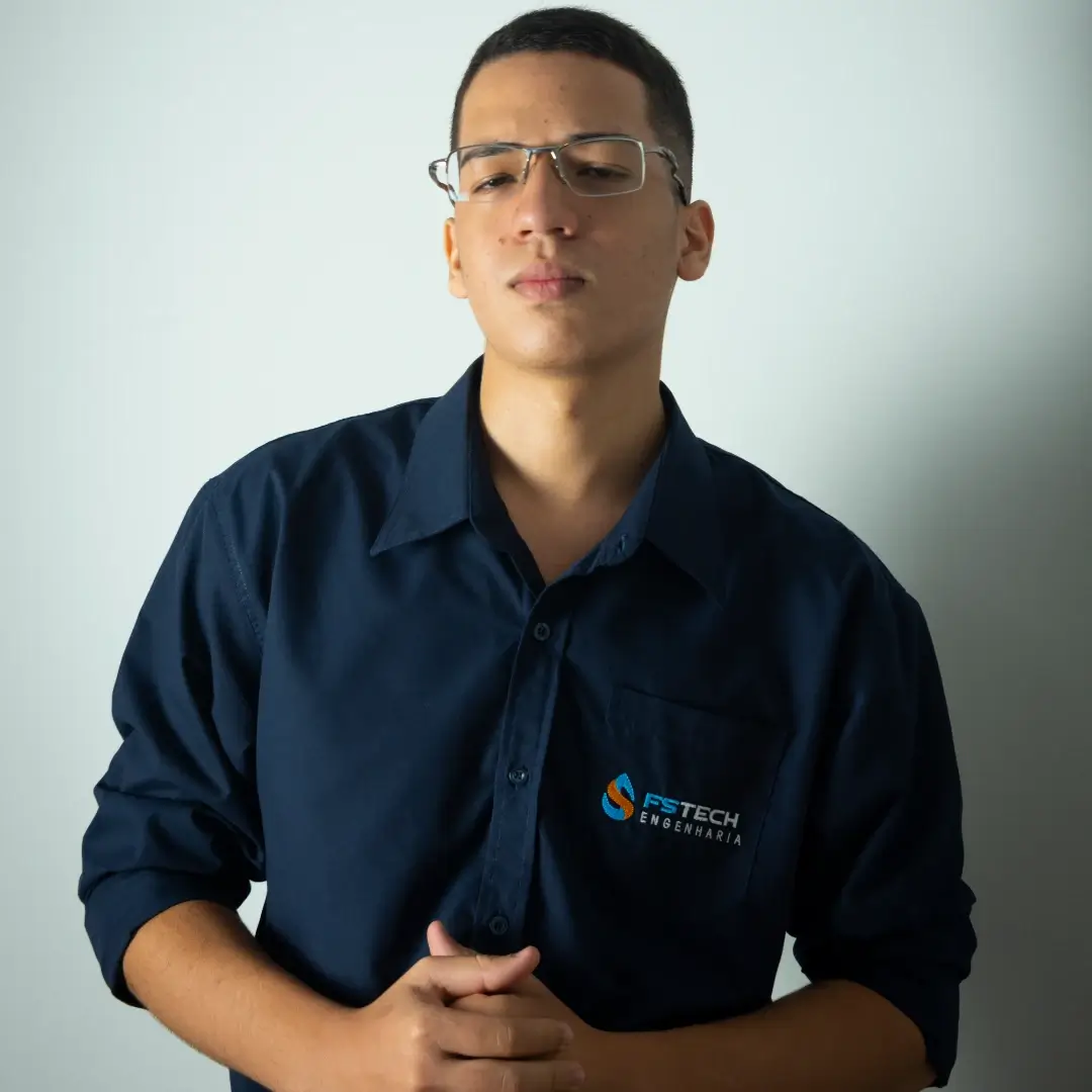 Jovem profissional com camisa azul escura e óculos, representando a empresa FS Tech Engenharia, em um cenário minimalista.